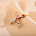 Close-up of golden letter X pendant with colorful cubic zirconia on beige fabric - Letter X