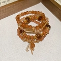 Close-up of four-piece beaded bracelet set featuring warm orange crystals and gold accents - Brown (4-Piece Set)