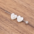 Detailed view of a gold letter D on a white heart brooch with a white pearl accent - Letter D