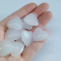 Mano sosteniendo corazones de cuarzo blanco pulido para cura y decoración - Blanco