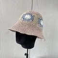 Dettaglio di un cappello da sole all'uncinetto con base rosa e motivi floreali blu - Rosa