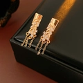 Detailed close-up of golden floral tassel earrings with zircon stones on black leather box - Earrings - Silver Pin Gold (Real Gold Plated)