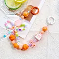 Close-up of candy-colored beaded phone strap with alphabet beads on decorative background - M Round Tag / Orange