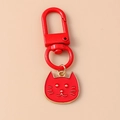 Primo piano di un portachiavi a forma di gatto in metallo rosso con bordo dorato - Stile Testa di Gatto Rosso