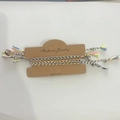 Detail of colorful woven bohemian bracelets with metallic beads on a display card - Light-Colored Woven Bracelet Set