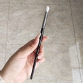 Single eye makeup brush with black handle, silver ferrule, and white bristles held by hand - Budget White Bristle Blending Brush
