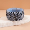 Detail of blue acrylic leopard print bracelet displayed on natural white stone base - Blue