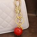 Portachiavi dorato con ciondolo a mela rossa appeso a una borsa trapuntata bianca di lusso - Ciondolo Mela Oro Chiaro