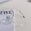 Elegant gold wavy metal headband with white pearls on a minimalist white surface - Wave Pearl Gold