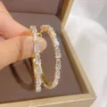 Close-up of gold hoop earrings with channel-set rectangular zircons on brown velvet - Channel Set Baguette Zircon (E1835 Gold) / 925 Silver Needle / Gold