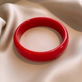 Close-up of a glossy red resin bangle on elegant champagne silk fabric texture - Bracelet-Red