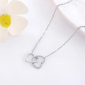 Gros plan du collier coeur entrelacé argenté sur un fond en tissu blanc doux - 9196-argent
