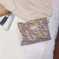 Detailed view of floral makeup bag with Time to Party label on a soft bed background - Black with Red and Yellow Daisy