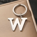 Silver metal letter W keychain pendant with polished finish on a textured gift box - Letter W