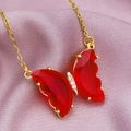 Macro detail of golden necklace featuring a red crystal butterfly pendant on purple silk - Red