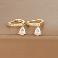 Detail of gold huggie earrings with a pear-cut cubic zirconia drop on brown texture - Gold White Zirconia