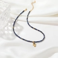 Lapis-Lazuli Perlenkette mit goldenem Hamsa-Hand-Anhänger auf weißem Seidenhintergrund - Lapislazuli Halskette