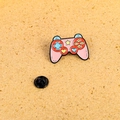 Nahaufnahme der rosa Emaille-Anstecknadel im Gamepad-Design mit buntem Tasten-Detail - Gamecontroller