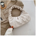 Primer plano de un bolso de nube plisado color crema sobre una chaqueta blazer caqui - Blanco Roto