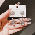 Macro shot of silver spider earrings with moonstone detailing on a jewelry card - Silver