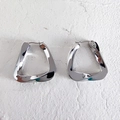 Vista macro de pendientes triangulares retorcidos de plata con acabado pulido espejo - Grande / Plateado