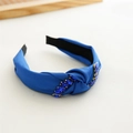 Detailed view of a blue knotted fabric headband embellished with faceted blue rhinestones - Blue