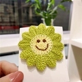Handmade knitted sunflower hair clip with a smiling face on a green crocheted petal - Green Smiley Flower