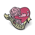 Cute enamel brooch featuring a brain and heart hugging with pink ribbon detail - Brain Heart Hug