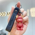 Dark red matte bear keychain with black wrist strap featuring embossed slogan lettering - Red