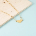 Vista detallada de un collar con colgante de corazón dorado y cadena de clip sobre piedra - Dorado