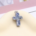 Natural blue dalmatian stone cross pendant with silver metal clasp on display - Blue Spot Stone