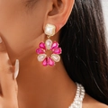 Nahaufnahme von Blumenohrringen mit rosa Kristallen und Perlen an einem Modell - Silberstift-Ohrringe / Rosa