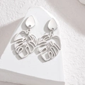 Detail of silver monstera leaf earrings on a minimalist white stone pedestal background - Silver Hollow Leaf Stud Earrings (E941-01-SD)