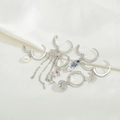 Silver earring set with star studs, pearl drops, and zircon dolphin charms on white silk - Silver