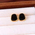 Close-up of vintage gold earrings with black velvet inlay on a jewelry box background - Square / Black