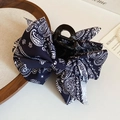 Détail d'une pince à cheveux à nœud en tissu paisley marine sur plateau en bois - Pince à nœud / Bleu
