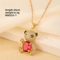 Detailed close-up of gold plated bear necklace with red heart stone and white zircon pave - Gold - Red Oval Stone Bear