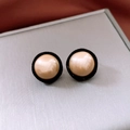 Close-up of beige faux pearl stud earrings with black flocking detail on a silver box - Silver Pin - Black - Champagne