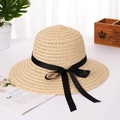 Detailed macro view of woven straw texture and elegant black ribbon bow on sun hat - Beige
