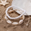 Detailansicht der gewebten Muschelfußkettchen mit weißen Perlen auf dem Sandstrand - 2-teiliges Fußkettchen-Set (D1688-1)