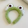 Macro view of green plush frog headband with soft texture and large cartoon eyes - Heart Frog Hairband