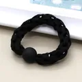 Detail of black woven elastic hair tie featuring a matte textured bead on a neutral surface - Black
