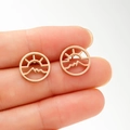 Close-up of rose gold hollow circular earrings with sunrise and mountain silhouette - Rose Gold