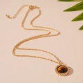 Detalle de un colgante redondo de ojo de tigre con un marco de metal dorado trenzado - Collar de Ojo de Tigre Marrón