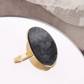 Detail of gold open ring with oval black marble inlay on a reflective mirror surface - Black