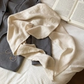 Dettaglio della trama della sciarpa in maglia crema su un cappotto di lana grigio - Bianco
