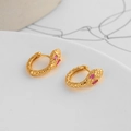 Macro shot of golden snake hoop earrings with purple gemstone eyes on white backdrop - Gold (Pink Eyes)