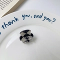 Mini hair claw with black and white checkerboard pattern on a white ceramic plate - Argyle Grey-Black