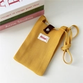 Dettaglio mini borsa in maglia gialla con fibbia marrone ed etichetta Hilldi sulla scrivania - 12*20cm / Giallo