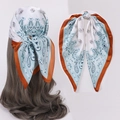 Detail of paisley print silk scarf tied in hair and knotted, blue and caramel tones - Coffee